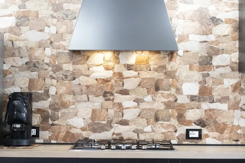 Kitchen with black units and exposed stone