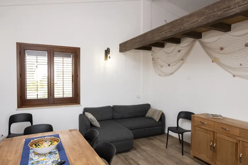 The living room: a sofa beside the shuttered window, against cool stone walls