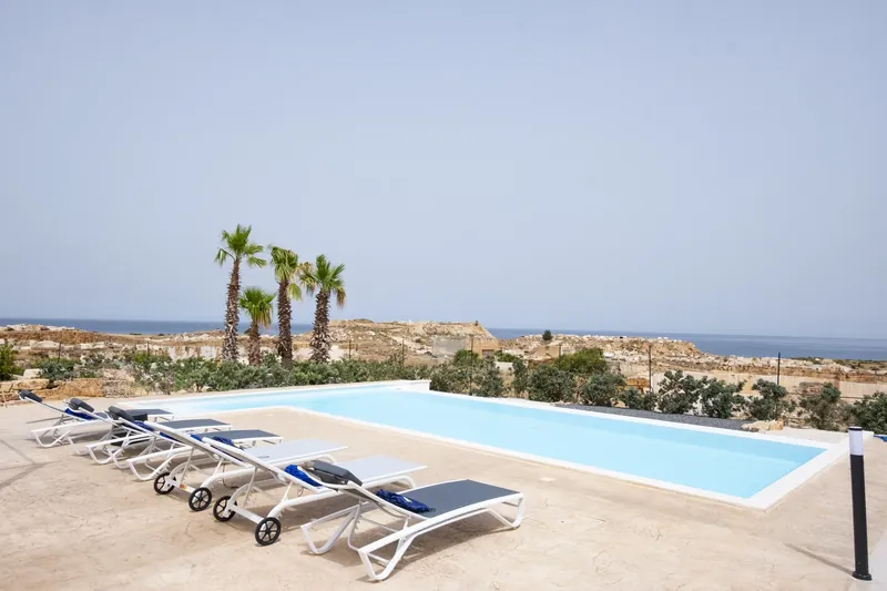 Sun loungers by the pool with the sea beyond