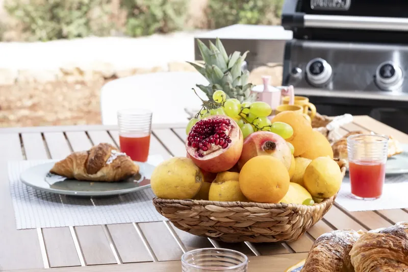 Outdoor dining table set for breakfast, palms and the sea beyond